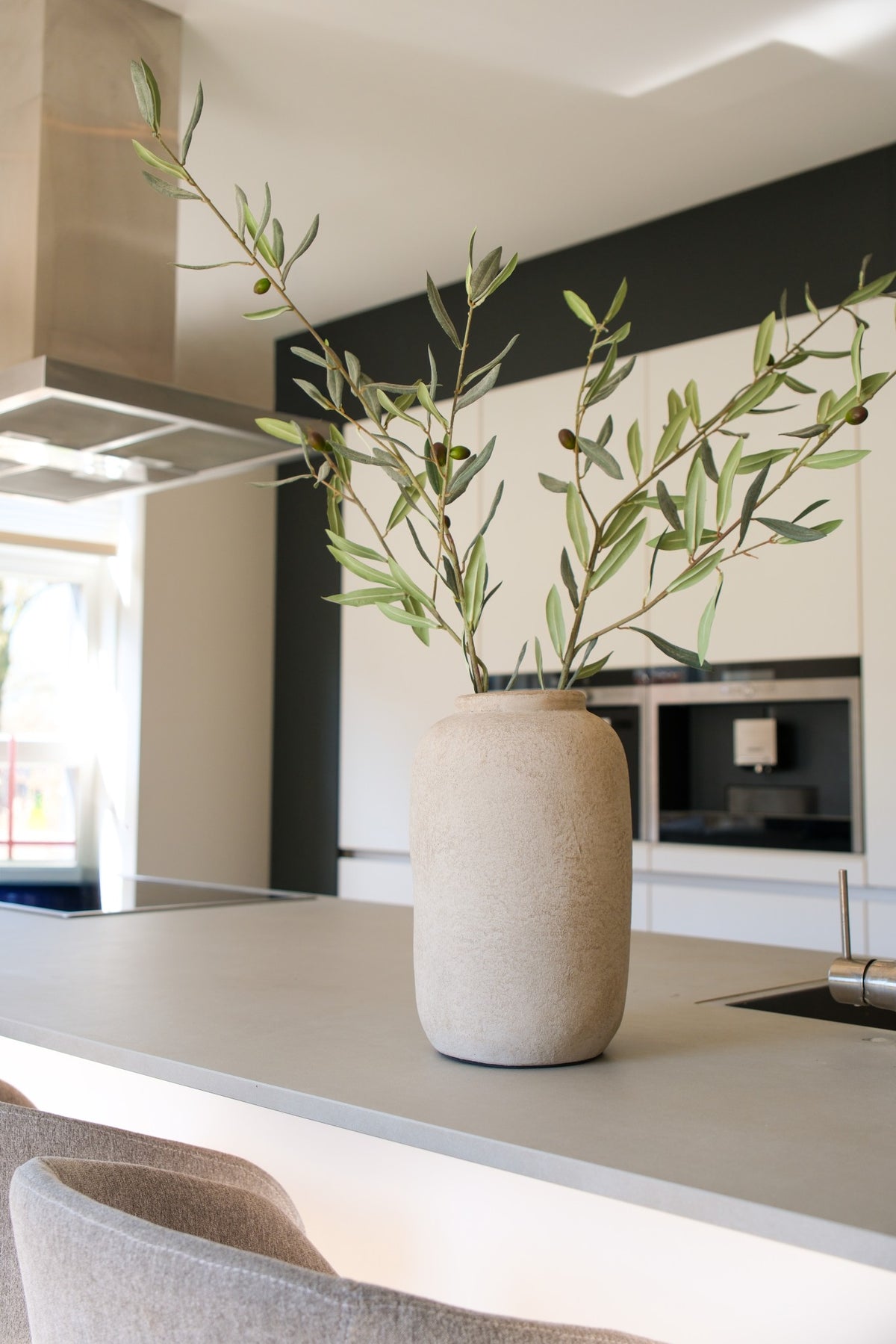 Light flesvaas van aardewerk met olijftakken in modern interieur