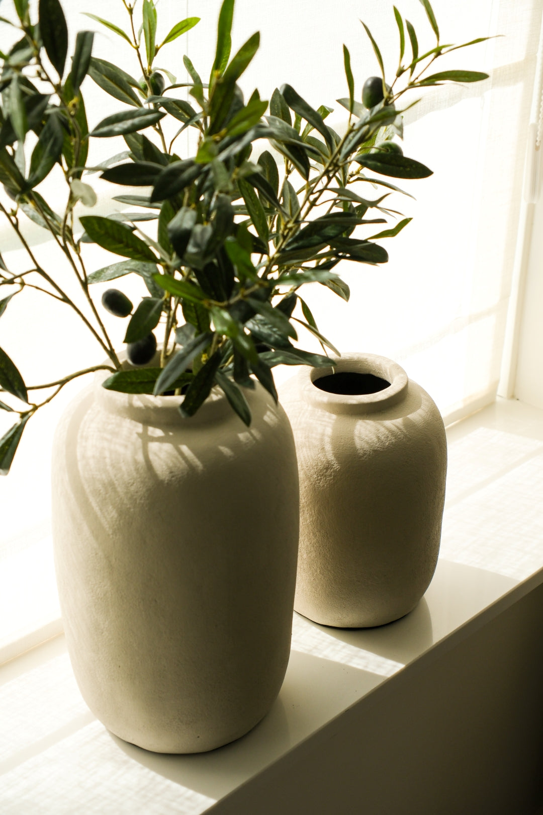 Beige aardewerk vaas met olijftakken in modern interieur