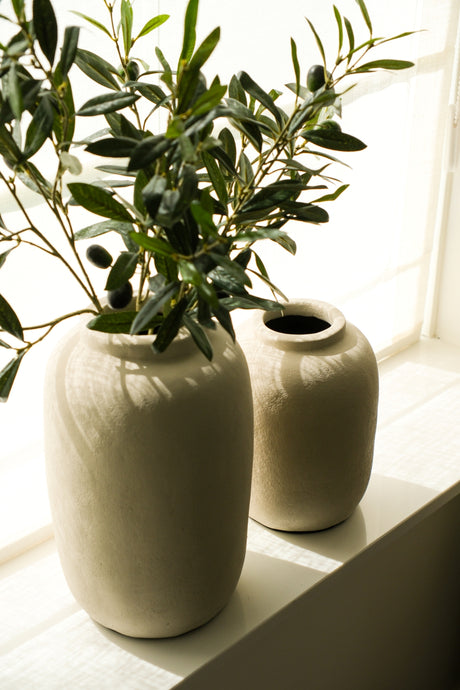 Beige aardewerk vaas met olijftakken in modern interieur