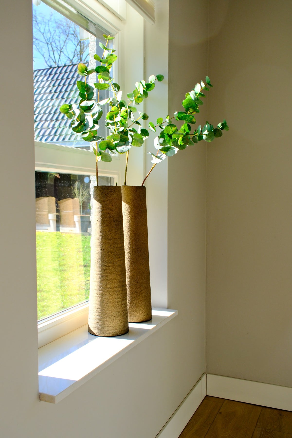 Hoge vaas Latte 40x12 cm met decoratieve takken op een vensterbank